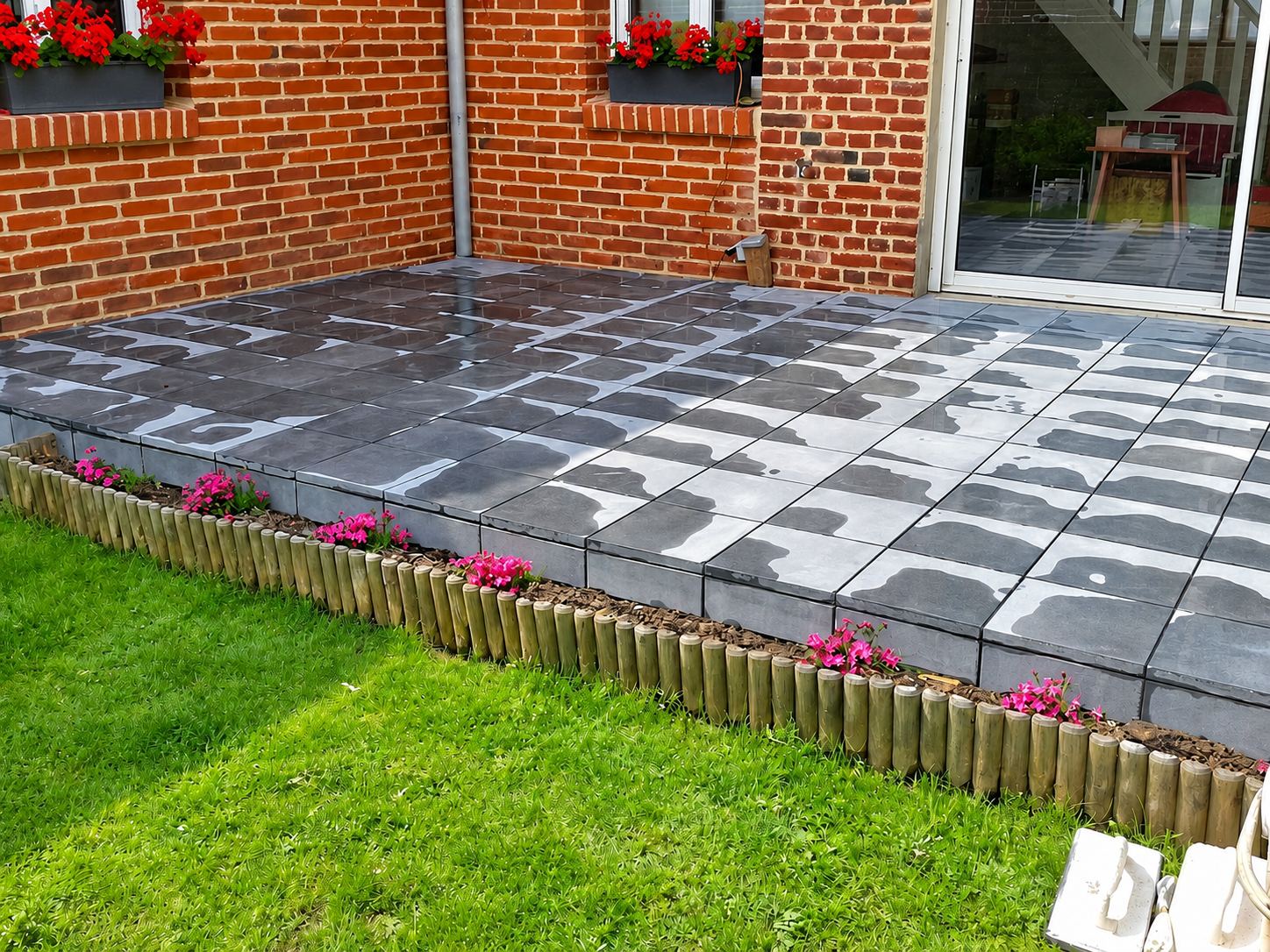 Terrasse en dalles grises neuves devant une maison en briques rouges